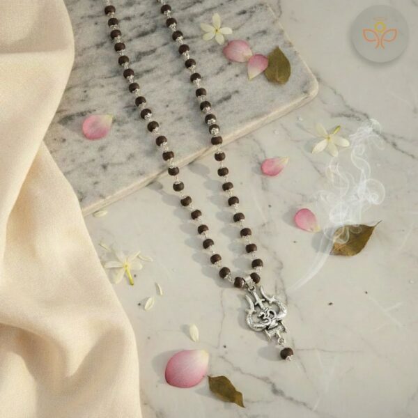 The OM Shiva Trishool Karungali Mala is a powerful spiritual rosary made from pure Karungali (Black Ebony) beads, combined with the sacred symbols of OM, Shiva, and Trishool. Karungali is known in ancient texts for attracting protection, strength, stability, and divine energy. This mala enhances spiritual growth, shields against negativity, and connects the wearer deeply with Lord Shiva’s cosmic energy. Perfect for meditation, japa, healing practices, and daily spiritual protection. Key Features Made from 100% natural Karungali / Black Ebony wood Powerful combination of OM, Shiva, and Trishool symbols Strong elastic thread for daily wear Smooth, hand-polished beads Lightweight, comfortable & energy-enhancing Suitable for men & women Ideal for meditation, chanting & protection Spiritual Benefits Protects from negative energies and evil influences Strengthens inner confidence & mental stability Enhances concentration and meditation power Attracts divine blessings of Lord Shiva Balances mind, body, and spiritual aura Helps in healing emotional stress & anxiety Brings peace, grounding, and spiritual clarity Who Should Wear This Mala? Shiva devotees People seeking protection from negativity Individuals suffering from stress and overthinking Those who meditate or practice yoga Anyone wanting spiritual growth and energy balance 🔱 How to Use / Puja Vidhi (English) Purify the mala with Ganga Jal or incense smoke. Hold it in your right hand and chant: “Om Namah Shivaya” Wear it daily or keep it on your altar for divine energy. Use it for meditation, japa, or spiritual healing.